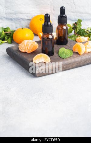 Huile de mandarine aromatique dans une bulle sombre, huile cosmétique de mandarine sur fond gris clair, espace de copie Banque D'Images