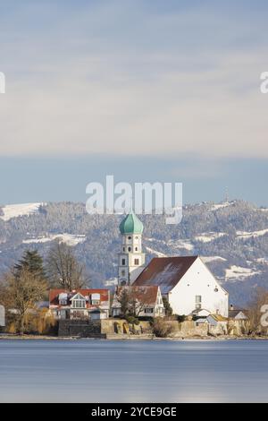 Église Saint-Georges avec tour verte en face de Pfaender enneigée, entourée de maisons de village, château à douves, lac de Constance, Bavière, Allemagne, Banque D'Images