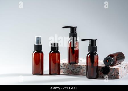 Élégantes bouteilles en verre ambré exposées sur une surface en pierre texturée dans un cadre de studio minimaliste Banque D'Images