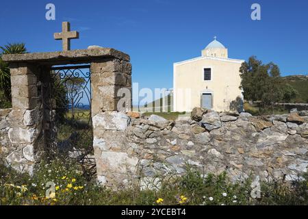 Bâtiment de l'église jaune derrière une porte en pierre, entouré par le ciel bleu et la nature, Chiesa di Agia Triada, église près de Marmari, Anatoliki Mani, Mani, Lacon Banque D'Images