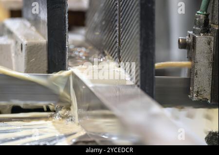 Scie à ruban automatique coupant la tige métallique avec la méthode de refroidissement à base d'eau. graphique Banque D'Images