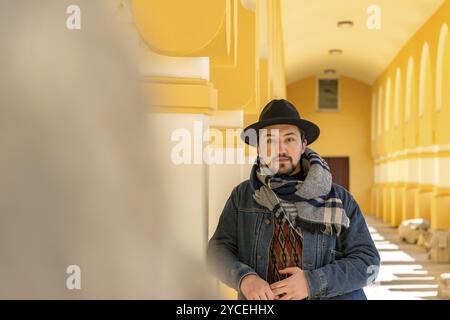 Portrait d'un beau jeune homme élégant avec une écharpe à l'extérieur. Un homme sérieux portant une écharpe, un chapeau et un jaket regardant confiant devant la caméra Banque D'Images