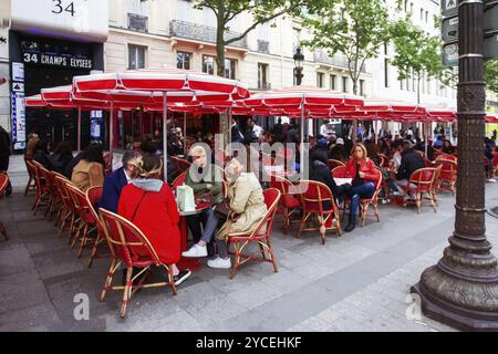 14-05-2016 PARIS. Café en plein air sur la rue champ-Elysées et les gens assis là sous des parapluies rouges Banque D'Images