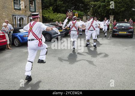 Stow on the Wold, Royaume-Uni, 12 août 2015 : des danseurs Morris dansent sur une place du village de Stow on the Wold dans les Cotswolds, tandis que certains touristes le sont Banque D'Images