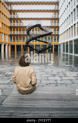 Munich, Allemagne, 03 mai 2015 : L'escalier infini d'Olafur Eliasson à Munich dans une cour d'un immeuble de bureaux. Femme d'âge moyen assise nea Banque D'Images