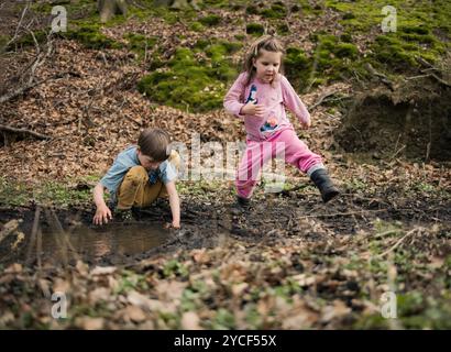 Enfants jouant dans une flaque dans la forêt Banque D'Images