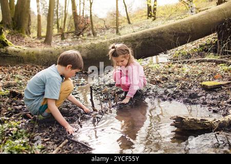 Enfants jouant dans une flaque dans la forêt Banque D'Images