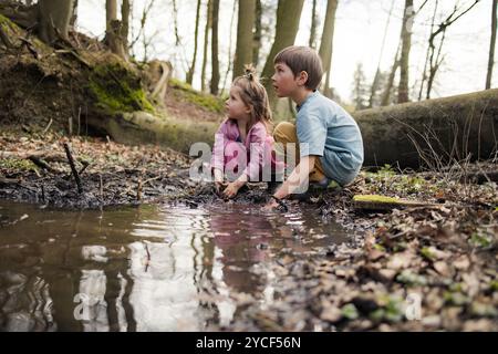 Enfants jouant dans une flaque dans la forêt Banque D'Images