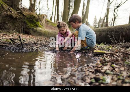 Enfants jouant dans une flaque dans la forêt Banque D'Images