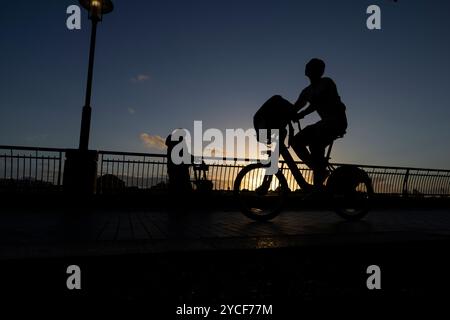 Les citadins qui rentrent chez eux pendant le coucher du soleil d'automne le long de la Tamise Pathway à Dundee Wharf, Westferry, Docklands, East London, Angleterre, ROYAUME-UNI Banque D'Images