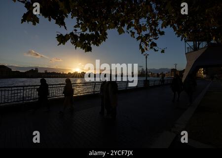 Les familles et les amis marchent en soirée pendant le coucher du soleil d'automne le long de la Tamise Pathway à Dundee Wharf, Westferry, Docklands, East London, Angleterre, ROYAUME-UNI Banque D'Images