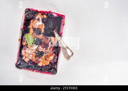 Tarte de cordonnier de mûrier maison sucrée, gâteau de cordonnier de baies d'été doux dans un plat de cuisson en émail et une assiette, sur un espace de copie de table de cuisine blanc Banque D'Images