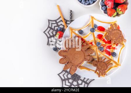 Petit déjeuner drôle pour les enfants pour Halloween. Crêpes sucrées maison créatives sous forme de monstres et symboles traditionnels d'Halloween, avec baies fraîches, chocolat Banque D'Images