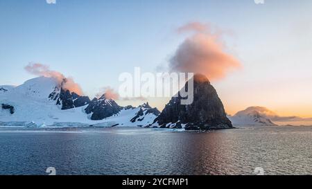 Nuage rouge brillant au-dessus d'un sommet de montagne sur la côte antarctique. Baie de Börgen, péninsule Antarctique, Antarctique. Banque D'Images