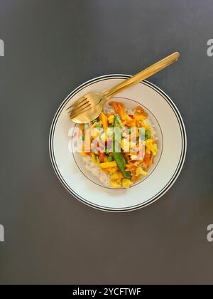 Un repas sans viande de riz cuit avec des légumes servis sur une assiette blanche sur un fond gris Banque D'Images