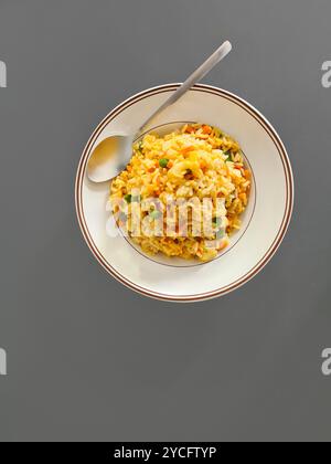 Un repas sans viande de riz cuit avec des légumes servis sur une assiette blanche sur un fond gris Banque D'Images