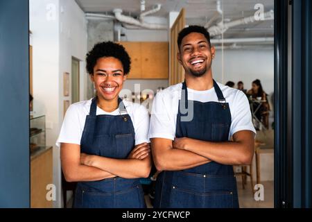 Boulangerie, portrait heureux de l'homme noir hispanique et la femme dans le café prêt à servir la pâtisserie, le café et les aliments cuits au four - serveur confiant barista par comptoir Banque D'Images