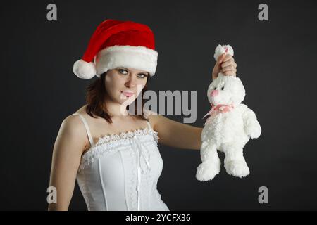 Femme en casquette de Noël tient dans la main un lapin blanc Banque D'Images