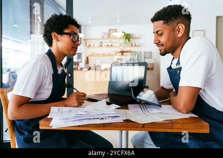 Boulangerie, portrait de l'homme et de la femme noirs hispaniques dans le café calculant les coûts et les taxes - les propriétaires de petites entreprises de suivi des revenus et des dépenses, en vérifiant b Banque D'Images