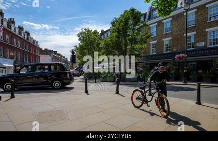 Londres - 06 15 2022 : vue sur Orange Sq avec taxi et enfant à vélo Banque D'Images