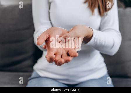 Gros plan d'une jeune femme malsaine souffrant de douleur dans les mains ou le poignet assis sur le canapé à la maison, patiente touchant le poignet se sentant blessée douleur articulaire Banque D'Images