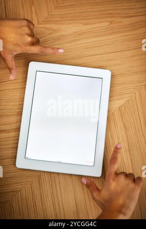 Personne, mains et maquette avec écran de tablette pour la publicité, le marketing ou l'application logicielle ci-dessus sur la table en bois. Vue de dessus, développeur et gros plan avec Banque D'Images