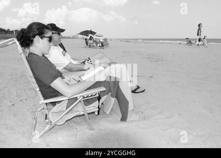 Couple caucasien se relaxant sur le Grand Strand à Myrtle Beach, Caroline du Sud, États-Unis. Femme lisant un livre sur la plage. Banque D'Images