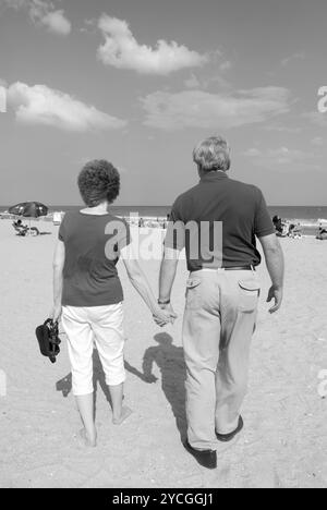 Couple âgé caucasien, 55 à 60 ans, se tenant la main et marchant le long de la plage de Grand Strand à Myrtle Beach, Caroline du Sud, États-Unis. Banque D'Images