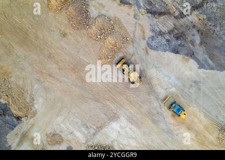 bulldozer à chenilles jaune effectue des travaux de terrassement sur chantier, vue aérienne depuis un drone. Banque D'Images