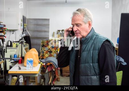 Upholsterer Talking Telephone le garçon tapissier de 75 ans fait ses derniers appels téléphoniques avant de prendre partiellement sa retraite et de déménager son entreprise à domicile. Tilburg, pays-Bas. Tilburg de Knop, Telefoonstraat Noord-Brabant Nederland Copyright : xGuidoxKoppesxPhotox Banque D'Images