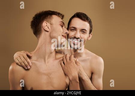 Un jeune couple heureux partage une étreinte intime, mettant en valeur leur amour dans une atmosphère chaleureuse. Banque D'Images