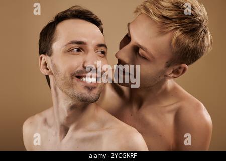 Deux jeunes hommes sourient brillamment alors qu'ils partagent un moment franc et affectueux dans un espace chaleureux. Banque D'Images