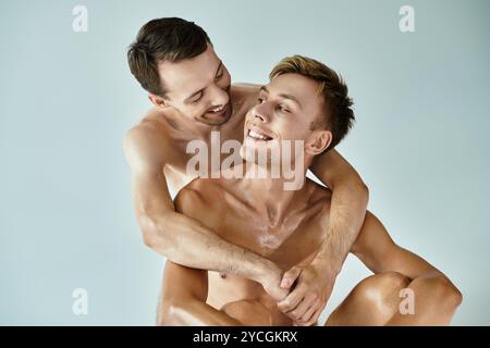 Deux jeunes hommes partagent une étreinte chaleureuse, souriant heureux l'un à l'autre dans un moment ludique d'amour. Banque D'Images