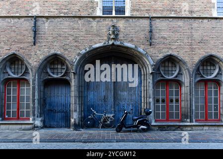 Fenêtres avec rebords peints en rouge vif et porte voûtée en bleu délavé sur le côté Wollestraat du beffroi de Bruges, Belgique Banque D'Images