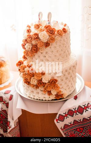 Elégant gâteau de mariage à deux niveaux orné de belles roses fondantes. Banque D'Images