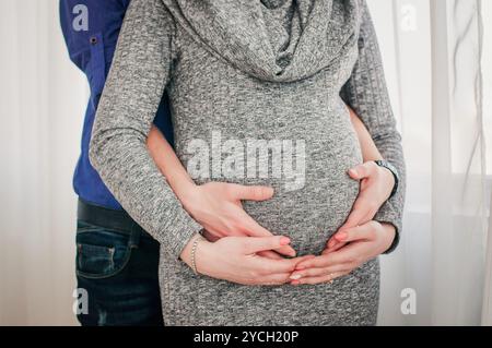 Tendre étreinte des parents qui attendent dans une pièce éclairée. Banque D'Images