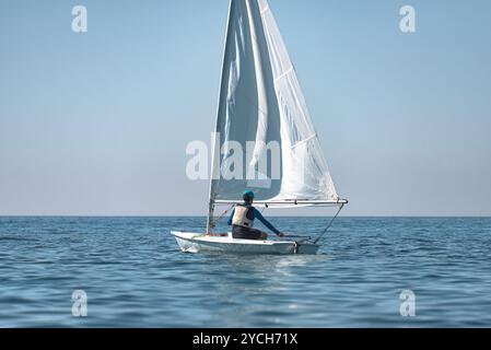 Jeune sportif navigue seul dans la mer par une journée ensoleillée Banque D'Images