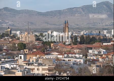 Vue panoramique de Nicosie, Chypre, mettant en valeur l'emblématique mosquée Selimiye au milieu d'une mer de toits, avec les drapeaux turc et TRNC en évidence Banque D'Images