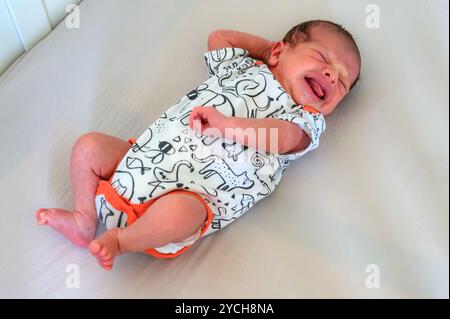 Un petit garçon se réveille et commence à pleurer pour attirer l'attention. Banque D'Images