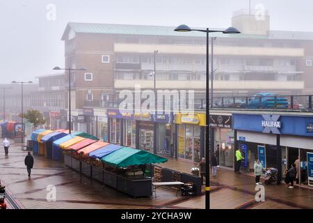 Boutiques et étals de marché sur Corporation Street, centre-ville de Corby, Angleterre, par une journée brumeuse. Banque D'Images