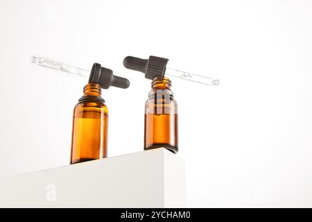 Deux pipettes avec sérum sont sur des cols de flacons ouverts bruns. Banque D'Images