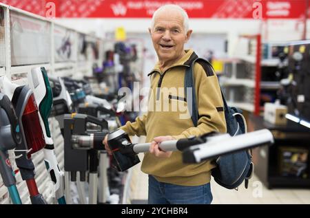 Senor homme retraité achetant aspirateur droit dans la salle d'exposition du magasin d'appareils électriques Banque D'Images