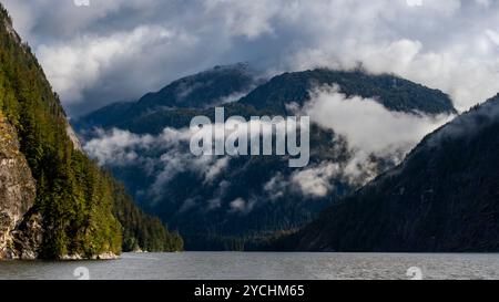 Des nuages brumeux entourent d'imposantes montagnes profondes dans le fjord de la forêt pluviale tempérée de Kynoch Inlet, Colombie-Britannique, Canada Banque D'Images