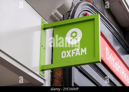 Enseigne suspendue de magasin de charité Oxfam sur le côté d'un bâtiment à Saffron Walden, Essex, Royaume-Uni. Banque D'Images