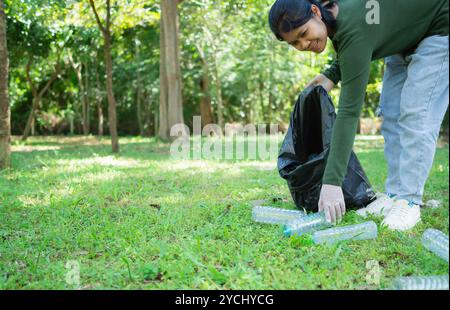 Femme de bénévoles dévoués participent à une activité de nettoyage environnemental dans un parc. Femme portant des gants et tenant de grands sacs noirs. Femme Banque D'Images