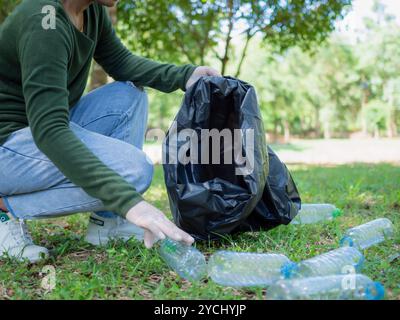 Femme de bénévoles dévoués participent à une activité de nettoyage environnemental dans un parc. Femme portant des gants et tenant de grands sacs noirs. Femme Banque D'Images