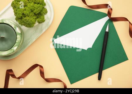 Ensemble élégant de papeterie de mariage. Modèles de cartes d'invitation de mariage, enveloppe verte, ruban de soie sur fond beige. Vue de dessus Banque D'Images