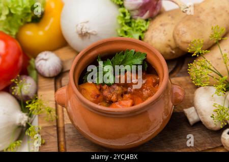 Rôti chaud en pot avec garniture sur planche de bois Banque D'Images