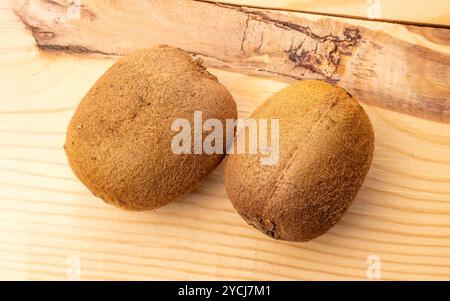 Deux kiwis juteux mûrs sur une table en bois, macro, vue de dessus. Banque D'Images