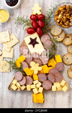 Plateau de charcuterie des fêtes en forme d'arbre de Noël composé de fromage, craquelins, saucisses, tomates, noix Banque D'Images